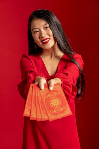 Modelo en vestido rojo mostrando tarjetas de año nuevo chino