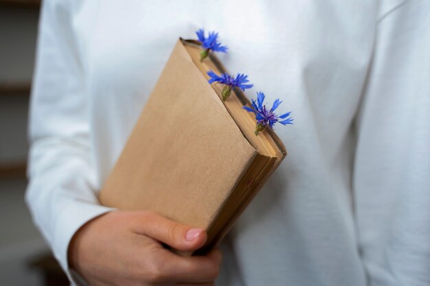 Modelo de vista frontal sosteniendo libro con flores.