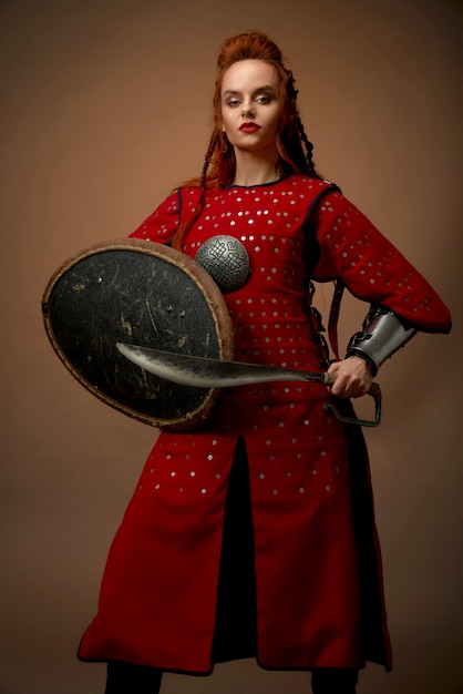 Foto gratuita modelo vistiendo traje medieval posando con daga, escudo
