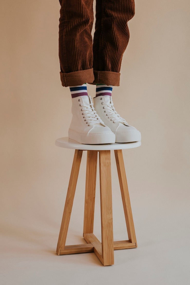 Foto gratuito modelo en zapatillas altas blancas de pie en una silla