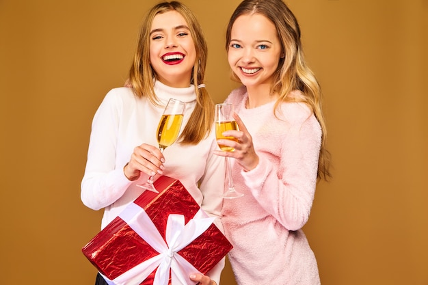 Modelos con caja de regalo grande bebiendo champán en copas celebrando el año nuevo