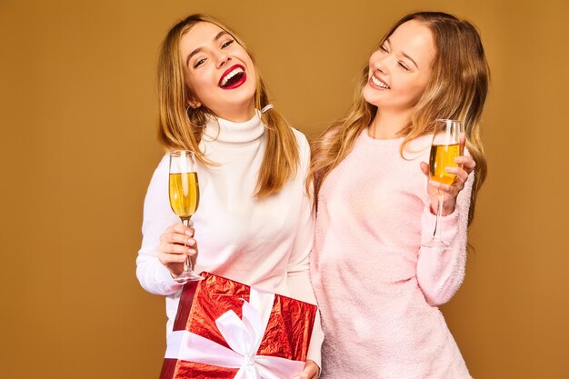 Modelos con caja de regalo grande bebiendo champán en copas celebrando el año nuevo