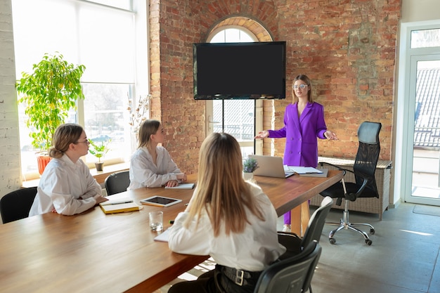 Foto gratuita moderno. mujer de negocios caucásica joven en la oficina moderna con el equipo. reunión, entrega de tareas. mujeres en el trabajo de recepción. concepto de finanzas, negocios, poder femenino, inclusión, diversidad y feminismo