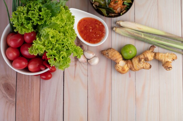 Mojar, limoncillo, ajo, lima, galanga, tomate y ensalada en el piso de madera