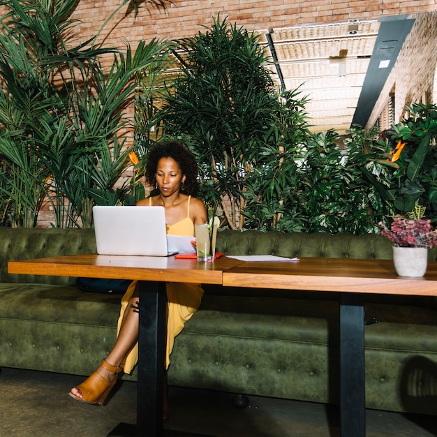 Foto gratuita mojito cocktail en mesa de madera con mujer joven trabajando en laptop