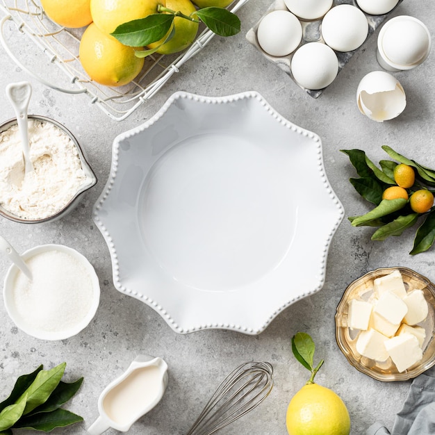 Molde para pasteles de cerámica blanca con ingredientes de limones para hacer un pastel de cuajada de limón sobre una mesa cuadrada de piedra blanca