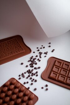 Moldes de chocolate marrón de silicona y chocolate en calettes sobre un fondo claro