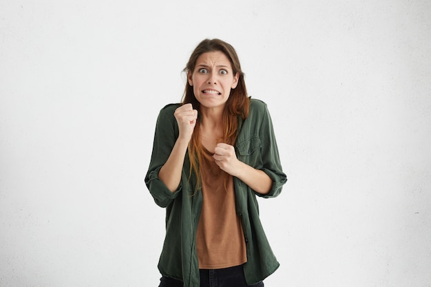 molesta irritada mujer enojada manteniendo los dientes apretados, su mueca y gesto expresando furia y locura. Mujer preocupada apretando los puños sintiéndose ansiosa y nerviosa, esperando algo