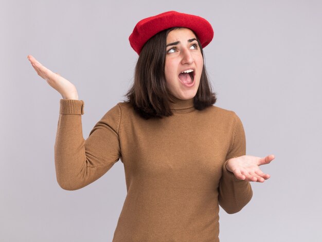 Molesta joven bastante caucásica con sombrero boina cogidos de la mano abiertos mirando al lado