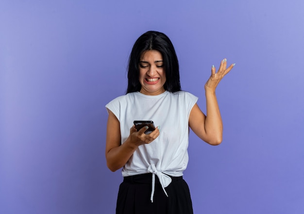 Molesta joven caucásica mira el teléfono y levanta la mano