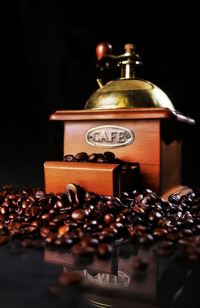 Foto gratuita molino de café sobre la mesa con granos de café alrededor