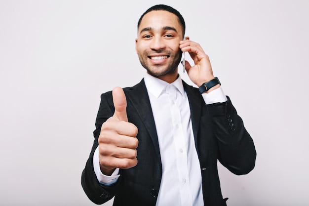 Momento exitoso del joven apuesto en camisa blanca, chaqueta negra que expresa positividad. Hablar por teléfono, liderazgo, gran carrera, gerente, buen humor.