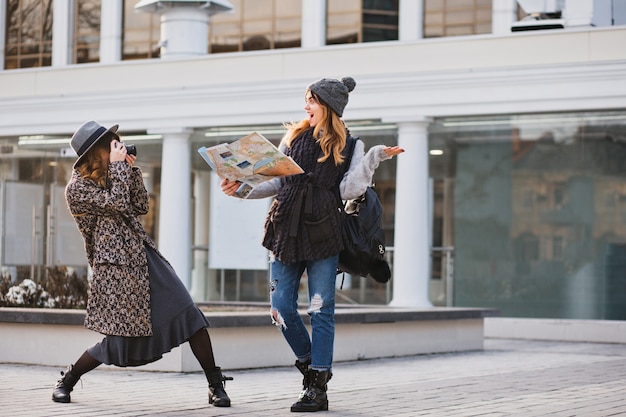 Momentos felices de turistas divertidos en un día soleado en una gran ciudad. Mujeres alegres y divertidas que viajan juntas, se divierten, hacen fotos, expresan verdaderas emociones positivas brillantes, apariencia elegante, mejores amigas.