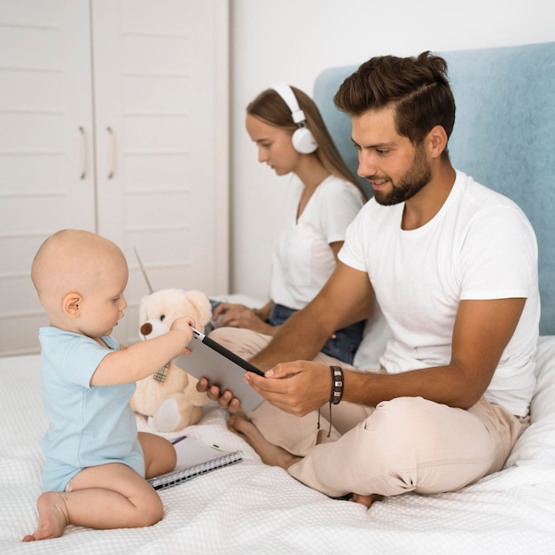 Foto gratuita mon trabajando desde casa durante la cuarentena mientras papá juega con el niño