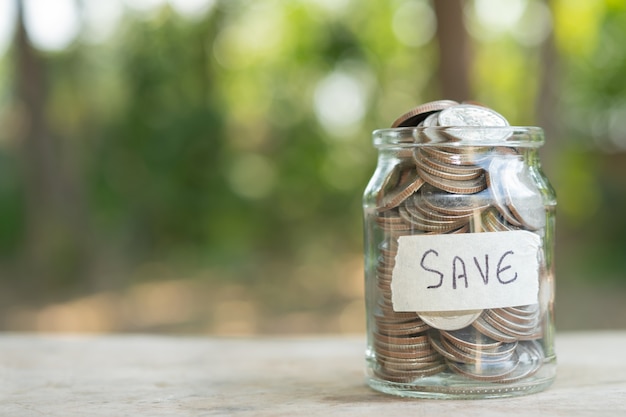 Monedas en frasco de vidrio para ahorrar dinero concepto financiero