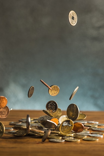 Foto gratuita las monedas de plata y oro y las monedas que caen en la pared de madera