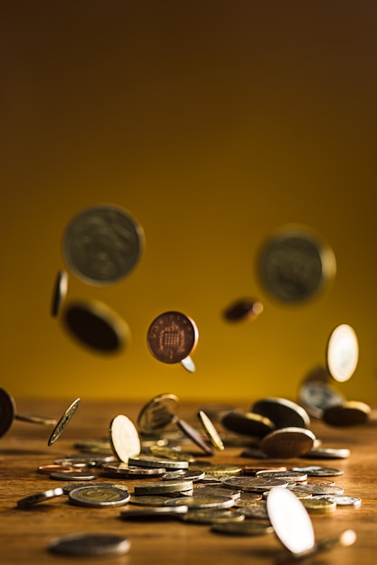 Las monedas de plata y oro y las monedas que caen en la pared de madera