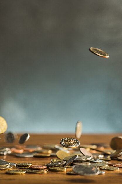 Las monedas de plata y oro y monedas que caen sobre fondo de madera