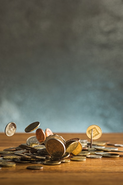 Las monedas de plata y oro y las monedas que caen sobre la mesa de madera