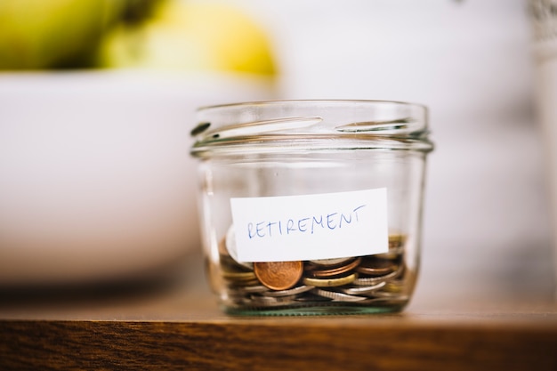 Monedas en un recipiente de vidrio abierto retiro en la mesa