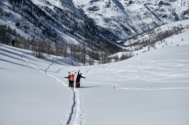 Montaña boscosa cubierta de nieve y gente caminando en Col de la Lombarde