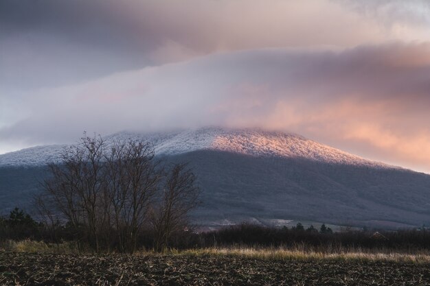 Montaña cubierta de nieve y un cielo nublado durante la puesta de sol