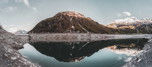 Montaña cubierta de verde reflejada en aguas tranquilas bajo un paisaje de cielo despejado