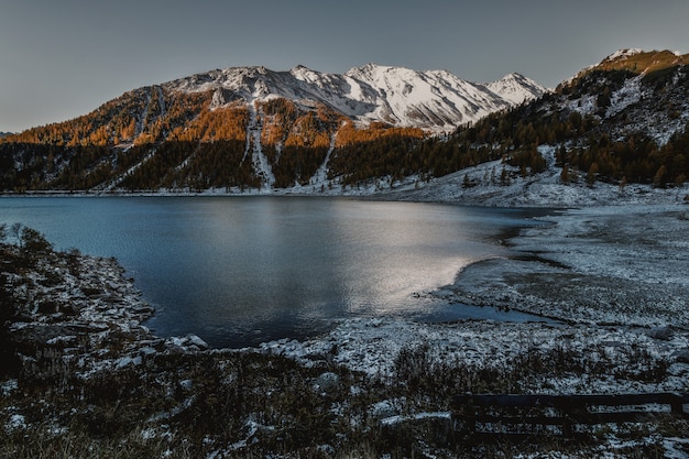 Montaña de gran altura marrón y blanca al lado del cuerpo de agua