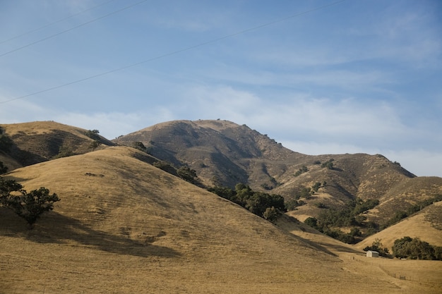 Montaña marrón y verde bajo un cielo azul durante el día