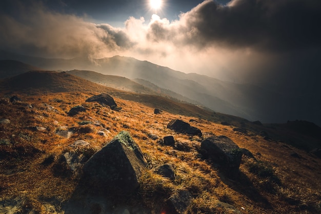 Foto gratuita montaña con piedras y un sol brillante durante el amanecer.