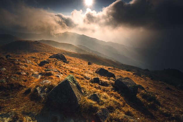 Montaña con piedras y un sol brillante durante el amanecer.