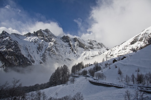 Montaña rocosa cubierta de nieve y niebla durante el invierno con un cielo azul en el