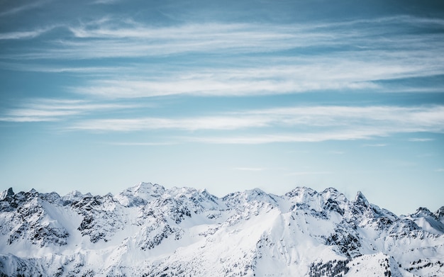 Montañas nevadas bajo un cielo azul nublado durante el día