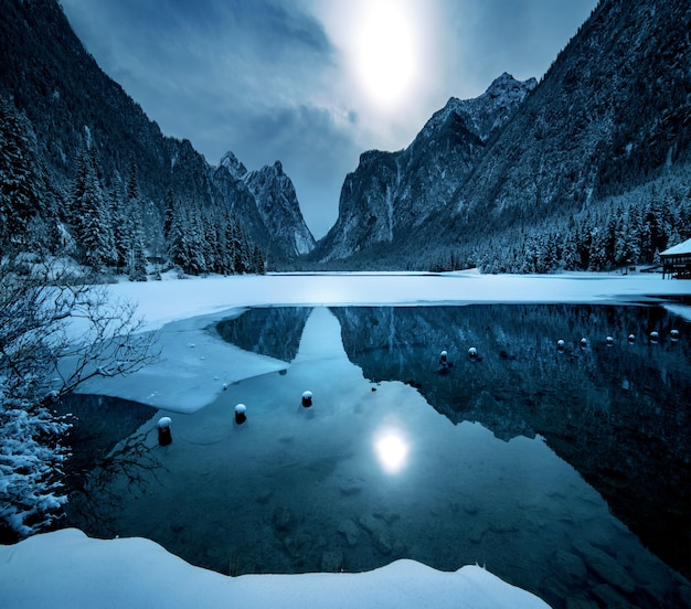 Montañas nevadas en Dolomiten se refleja en el lago de abajo