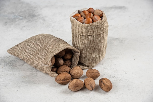 Montón de avellanas y nueces orgánicas en arpillera sobre mesa de mármol.