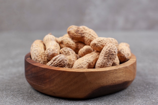 Montón de cacahuetes orgánicos en un tazón de madera