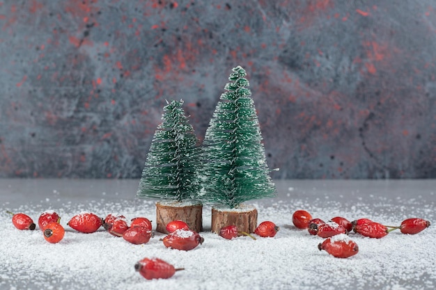 Montón de caderas, coco en polvo y figuras de árboles de Navidad en la mesa de mármol.