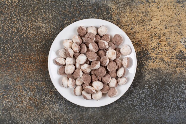 Montón de caramelos marrones en un plato blanco.