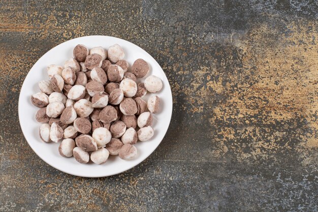 Montón de caramelos marrones en un plato blanco.