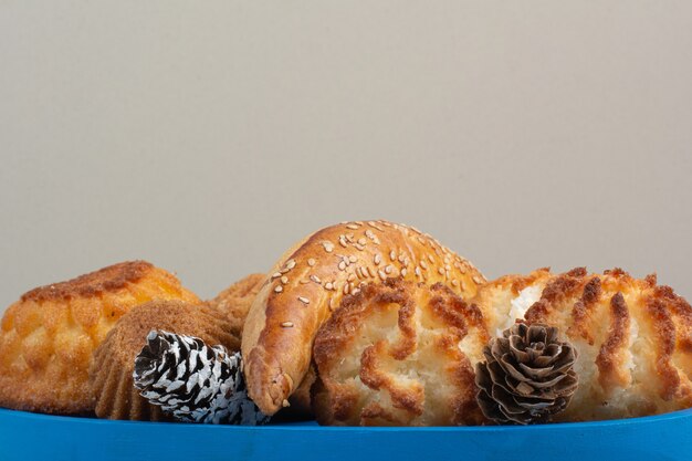 Un montón de deliciosas galletas frescas con pequeñas piñas en placa azul.