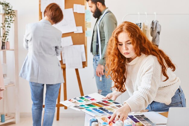 Montón de diseñador de moda trabajando en atelier con paleta de colores