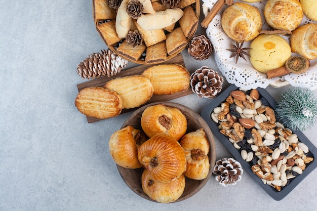 Montón de diversas galletas, nueces y piñas en tazones. Foto de alta calidad