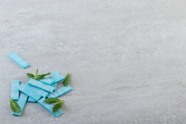 Montón de encías azules con hojas de menta en fondo gris.