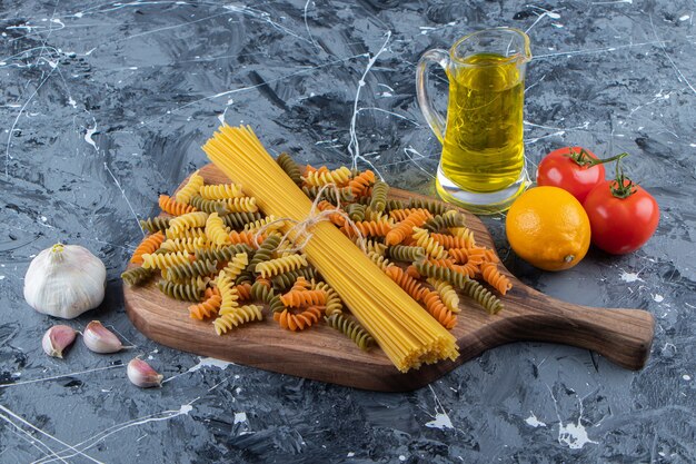 Montón de espaguetis crudos en cuerda con pastas y verduras multicolores.