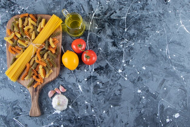 Montón de espaguetis crudos en cuerda con pastas y verduras multicolores.