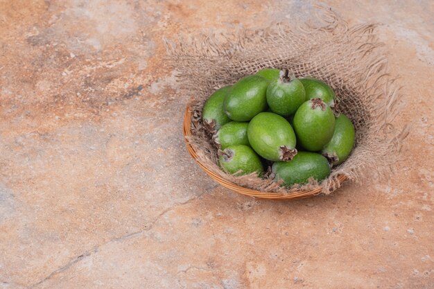 Montón de feijoas en un tazón sobre fondo naranja.