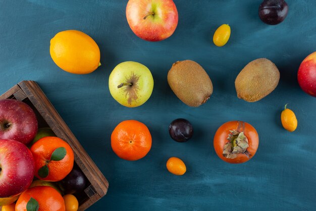 Montón de frutas frescas enteras colocadas sobre una superficie azul.