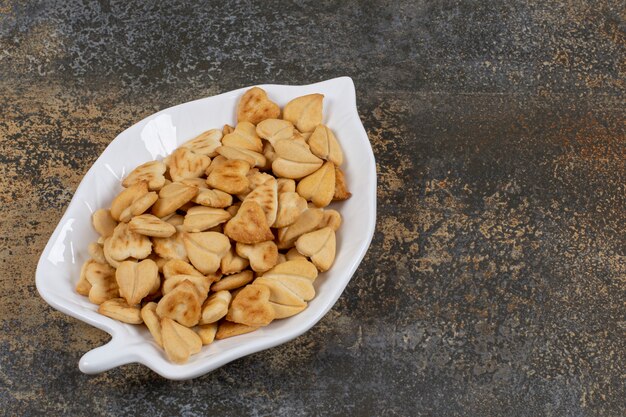 Montón de galletas en forma de corazón en placa con forma de hoja.