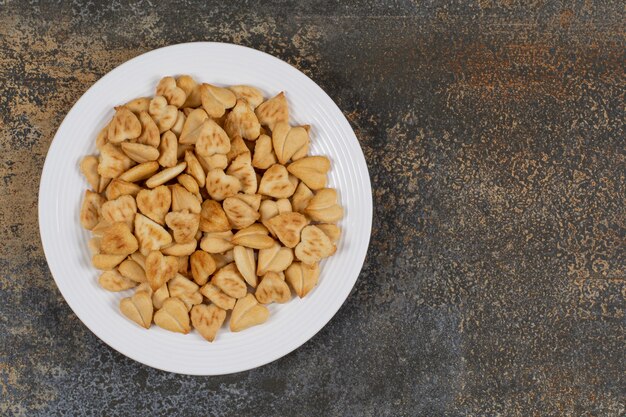 Montón de galletas en forma de corazón en un plato blanco.