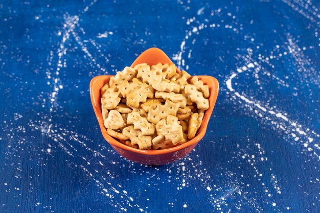 Montón de galletas saladas pequeñas colocadas en un tazón naranja.